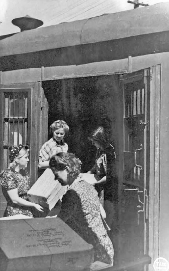 Стахановцы почты. Молодежная бригада почтового вагона Ленинград — Московского вокзала перевыполняет план обработки почты в пути. Начальник вагона В. И. Галахова со своей бригадой за погрузкой в вагон посылок. 9 июня 1943 г. Фото С. Кропивницкого. Фотохроника ТАСС